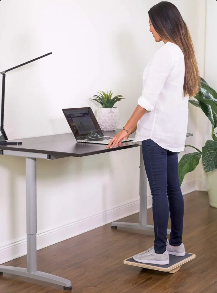 Woman working at a standing desk on a balance board